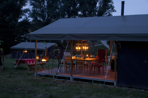 Et hyggeligt aftenbillede af en oplyst glampingtelt ved Feather Down Hohenwarter Seehof i Thüringen, Tyskland.