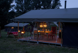 Et hyggeligt aftenbillede af en oplyst glampingtelt ved Feather Down Hohenwarter Seehof i Thüringen, Tyskland.