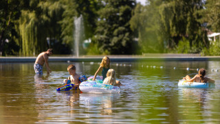 Niños juegan con flotadores y pistolas de agua en aguas poco profundas en Camping Papillon, Bélgica.
