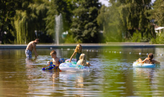 Niños juegan con flotadores y pistolas de agua en aguas poco profundas en Camping Papillon, Bélgica.