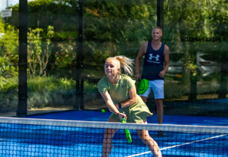 To personer spiller padeltennis på en udendørs bane ved Camping Papillon, en feriepark i Belgisk Limburg.