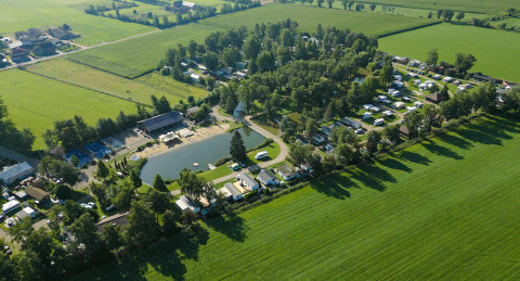 Vista aerea di un campeggio con stagno, circondato da campi verdi vicino a Kinrooi, Limburgo, Belgio.