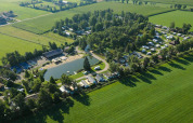 Vista aerea di un campeggio con stagno, circondato da campi verdi vicino a Kinrooi, Limburgo, Belgio.