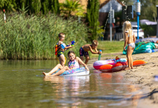 Bambini giocano con pistole ad acqua e gonfiabili sul lago al Camping Papillon nel Limburgo belga.