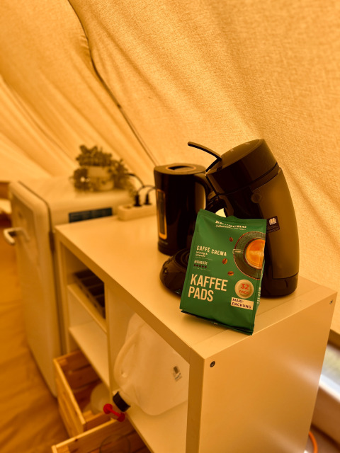 Koffiemachine, koffiepads en waterkoker op kastje in tipi-tent bij Camp Kyllburg, Duitsland.