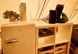 Interior de tienda Tipi en Camp Kyllburg, Alemania, con nevera, utensilios de cocina y cafetera.