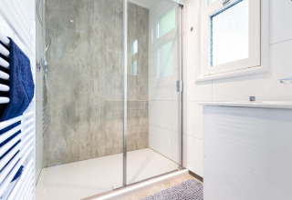 Moderne Dusche mit Glaswand, Handtuchheizkörper und Fenster im Special Wellness Module, Holiday Park Gelloo, Niederlande.