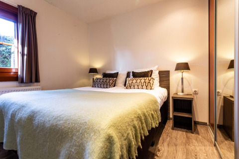Dormitorio en Log Cabin II Wellness en Résidence de Leuvert, Países Bajos, con cama doble y lámparas.