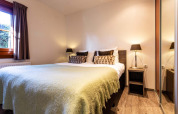 Dormitorio en Log Cabin II Wellness en Résidence de Leuvert, Países Bajos, con cama doble y lámparas.