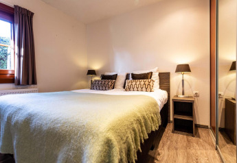 Slaapkamer van Log Cabin II Wellness in Résidence de Leuvert, Nederland, met dubbel bed en sfeervolle lampen.