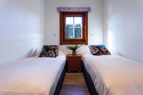 Acogedor dormitorio con dos camas individuales, ventana y planta en Log Cabin II Wellness, Países Bajos.
