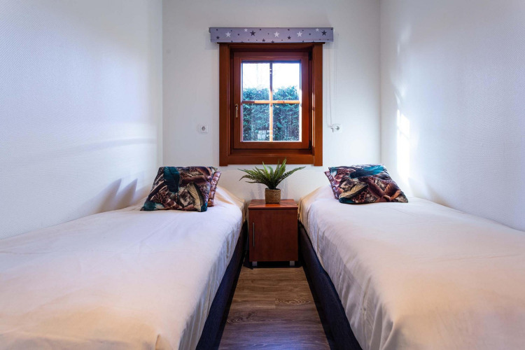Acogedor dormitorio con dos camas individuales, ventana y planta en Log Cabin II Wellness, Países Bajos.