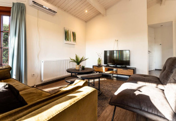 Sala de Log Cabin II Wellness en Résidence de Leuvert, Países Bajos, con sofás modernos y televisión.