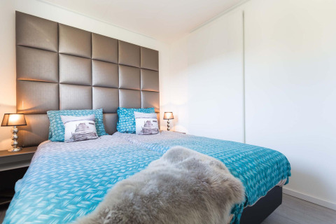 Chambre moderne au Collosseo Wellness Spa, Résidence Valkenburg aux Pays-Bas, avec literie bleue moderne.