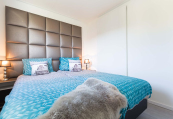 Dormitorio moderno en Collosseo Wellness Spa, Résidence Valkenburg, Países Bajos, con ropa de cama azul.