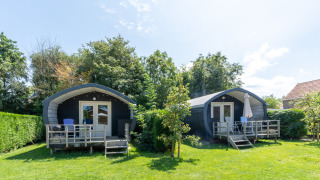 Zwei gemütliche Cocon-Hütten mit Terrasse und Gartenmöbeln, umgeben von Grün und Sonnenschein.