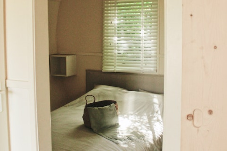 View into a cozy bedroom at the Cocon cabin in 7Huizen aan Zee, Netherlands, with a bag resting on the bed.
