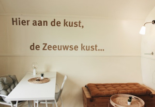Interior de la cabaña Cocon en 7Huizen aan Zee en los Países Bajos, con texto en neerlandés en la pared.