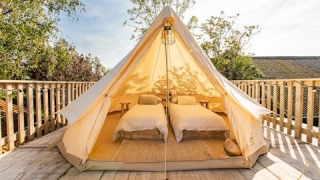 Entrance to Lodge 5 showing a luxury tent with two single beds, cozy decor and wooden deck outdoors.