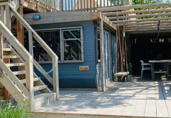 Lichte houten veranda en lodge met trap en schommel bij Lodge 5, 7Huizen aan Zee, Nederland