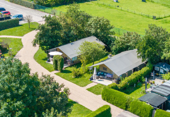Luftaufnahme von Safarizelten auf einem grünen Campingplatz mit Wegen, Hecken und Bäumen