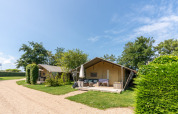 Safari telte på 7Huizen aan Zee i Holland med verandaer og grønne omgivelser under en blå himmel.