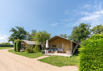 Safari telte på 7Huizen aan Zee i Holland med verandaer og grønne omgivelser under en blå himmel.