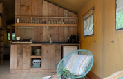 Inde i et safaritelt med træ køkken, blå stol og vinduer, Safari tent hos 7Huizen aan Zee, Holland.