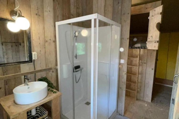 Salle de bain dans la tente safari à 7Huizen aan Zee aux Pays-Bas avec douche, lavabo et miroir.