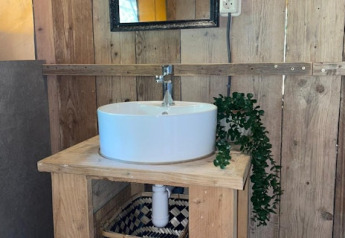 Baño rústico de madera con lavabo redondo y espejo en una tienda safari en 7Huizen aan Zee, Países Bajos.