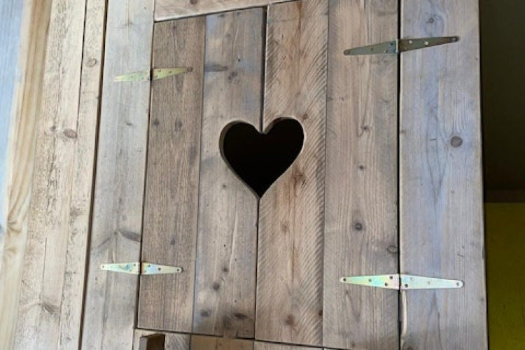 Wooden door with a heart-shaped cutout in a safari tent at 7Huizen aan Zee, Netherlands, close-up.