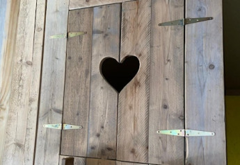 Wooden door with a heart-shaped cutout in a safari tent at 7Huizen aan Zee, Netherlands, close-up.