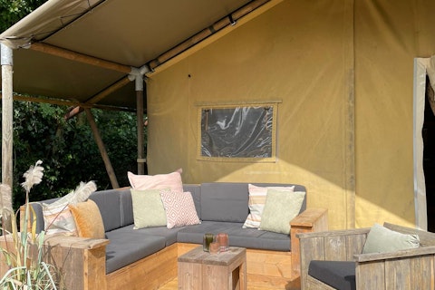 Gemütliche Sitzecke vor einem Safarizelt mit Sofas und Kissen bei 7Huizen aan Zee in den Niederlanden.