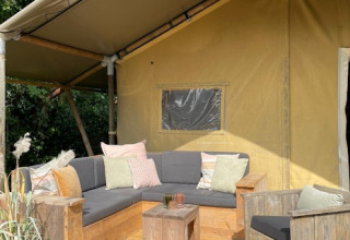 Gemütliche Sitzecke vor einem Safarizelt mit Sofas und Kissen bei 7Huizen aan Zee in den Niederlanden.