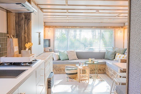 Lys og moderne lodge interiør med hyggelig sofakrog og åbent køkken hos Lodge 2 og 3, 7Huizen aan Zee, Holland.