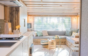 Lys og moderne lodge interiør med hyggelig sofakrog og åbent køkken hos Lodge 2 og 3, 7Huizen aan Zee, Holland.