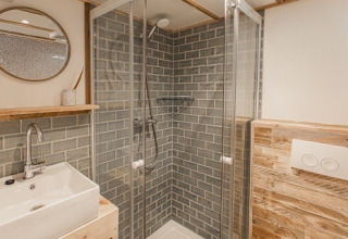 Moderne badkamer met glazen douche, wastafel en spiegel in Lodge 2 en 3 bij 7Huizen aan Zee, Nederland.
