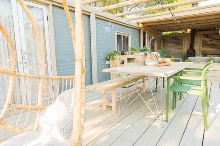 Terraza exterior en Lodge 2 y 3 de 7Huizen aan Zee, Países Bajos, con mesa de comedor, bancos y sillas verdes.