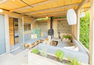 Gezellige loungehoek buiten bij Lodge 2 en 3 van 7Huizen aan Zee, Nederland, met planten en hout.