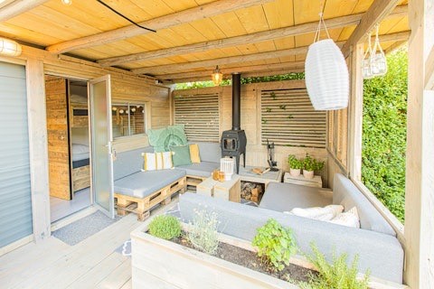 Area relax esterna al Lodge 2 e 3 di 7Huizen aan Zee, Paesi Bassi, con piante verdi e arredi in legno.