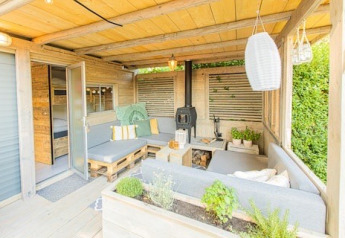 Gezellige loungehoek buiten bij Lodge 2 en 3 van 7Huizen aan Zee, Nederland, met planten en hout.