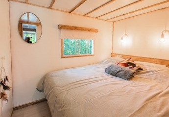 Bedroom with a large bed, round mirror and window, Lodge 2 and 3, 7Huizen aan Zee in the Netherlands.