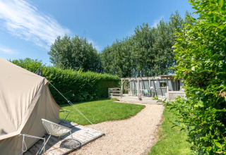 Buitenbeeld van Lodge 2 en 3 bij 7Huizen aan Zee in Nederland met een tent, tuin en houten terras.