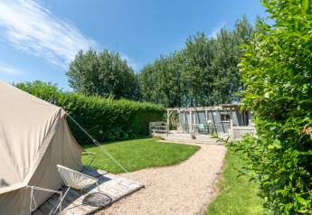 Vista esterna dei Lodge 2 e 3 a 7Huizen aan Zee nei Paesi Bassi con tenda, giardino e terrazza in legno.