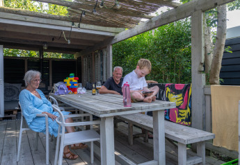 Familie entspannt auf Terrasse von Lodge 2 und 3, 7Huizen aan Zee in den Niederlanden im Sommer.