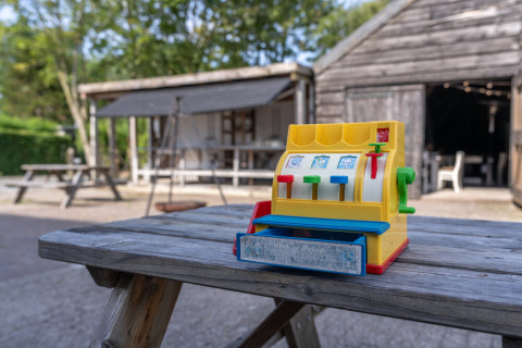 Eine bunte Spielzeugkasse steht auf einem Holztisch vor einer Hütte bei Lodge 2 und 3, 7Huizen aan Zee.