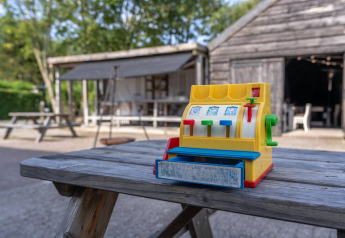 Eine bunte Spielzeugkasse steht auf einem Holztisch vor einer Hütte bei Lodge 2 und 3, 7Huizen aan Zee.