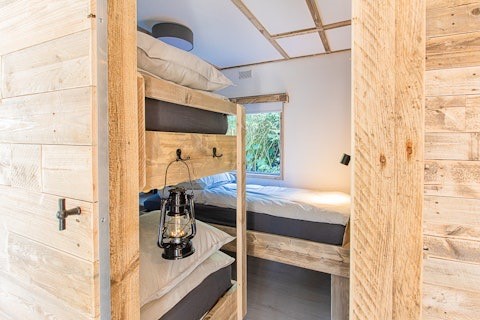 Interior of Lodge 1 and 4 at 7Huizen aan Zee in the Netherlands featuring wooden bunk beds and decor.