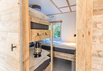 Innenansicht der Lodge 1 und 4 bei 7Huizen aan Zee in den Niederlanden mit Holzbetten und Fenster.