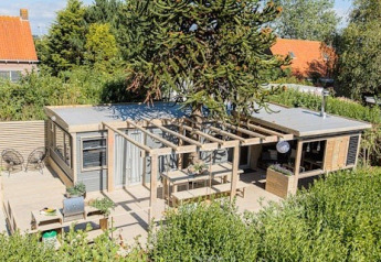 Außenansicht von Lodge 1 und 4 bei 7Huizen aan Zee in den Niederlanden, mit Terrasse und viel Grün.
